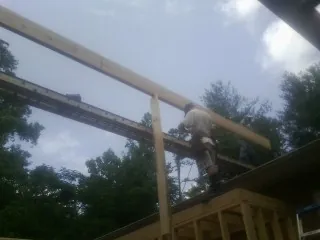 Carpenter setting a ridge beam over a new addition frame — Ice Dam Removal by Roofing Brothers in Ehrhardt