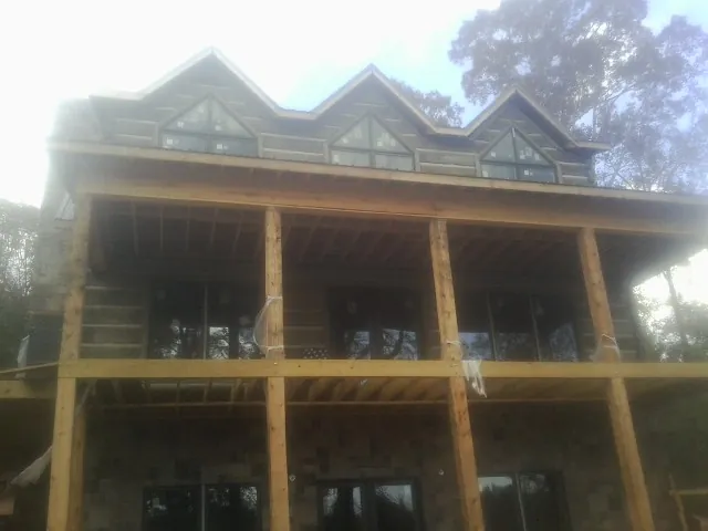 Dormers and porch framing on a large log home under construction — Roof Coating work by our crew in Ehrhardt
