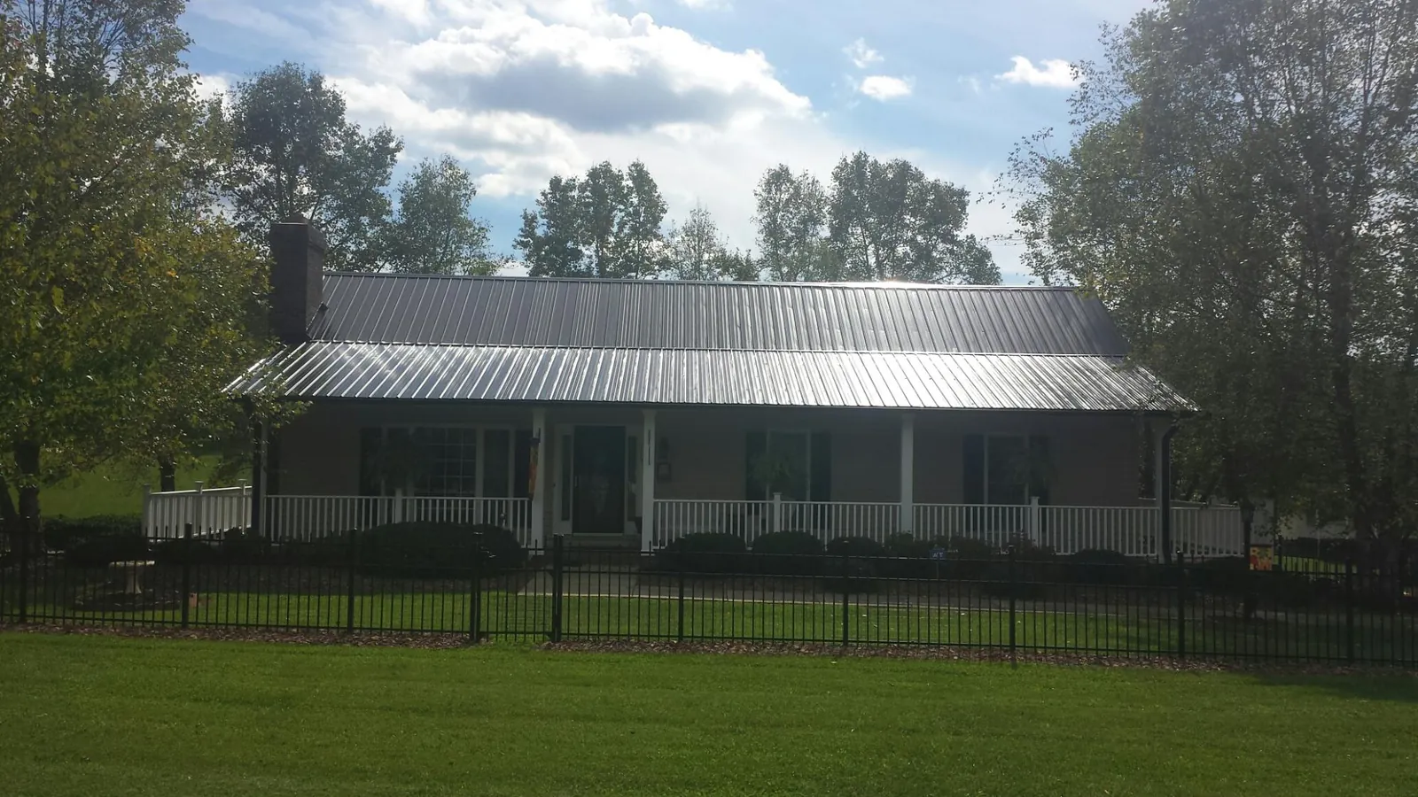 Gray metal roof on a brick ranch with a full width front porch — Gutter Guard Installation work by our crew in Ehrhardt