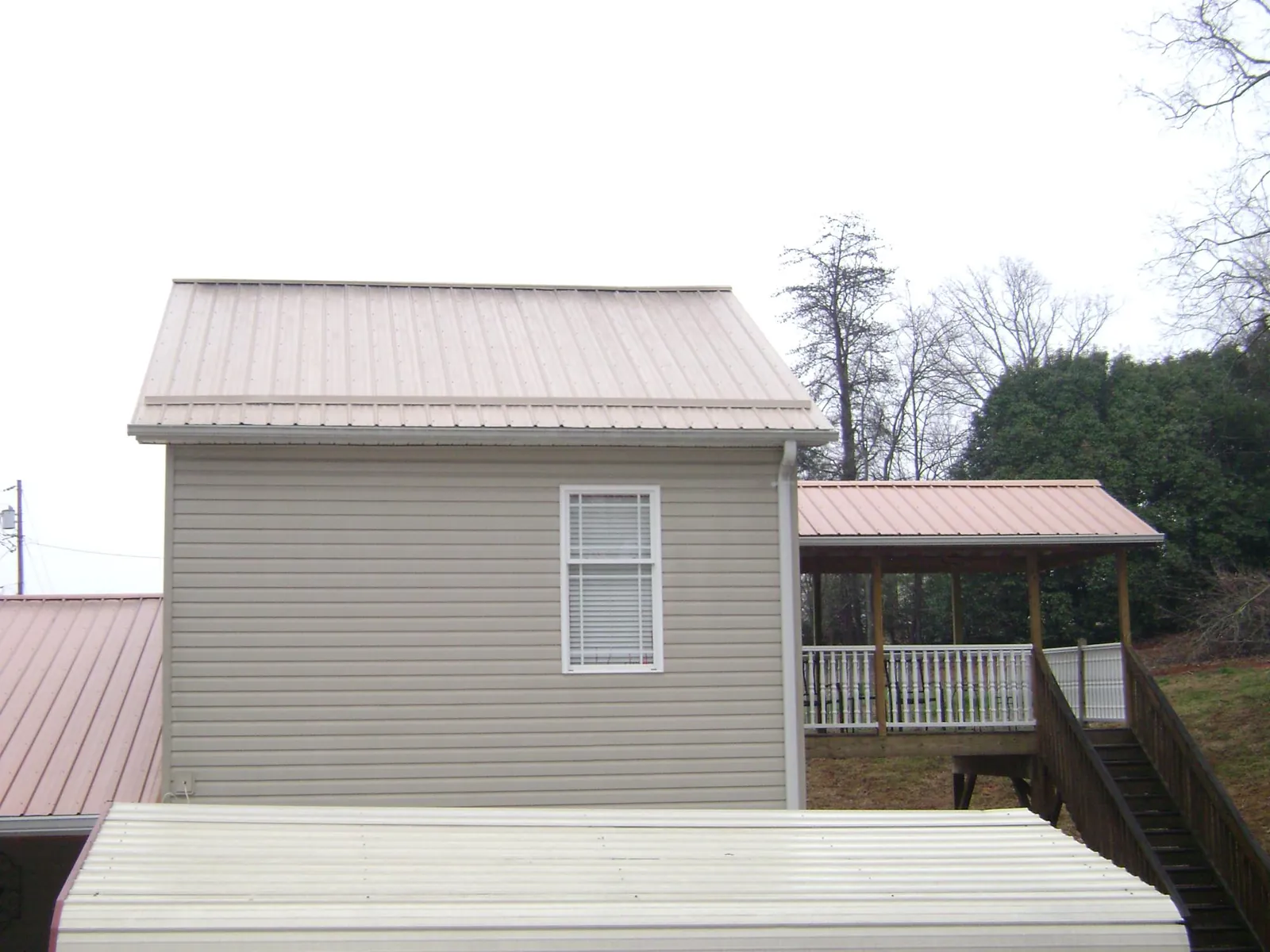 Tan metal roofs on a two story addition and attached porch, from a Roof Replacement job in Ehrhardt